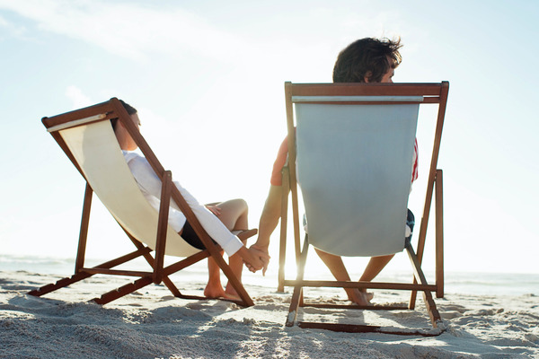 Couple sitting on sand in beach chairs